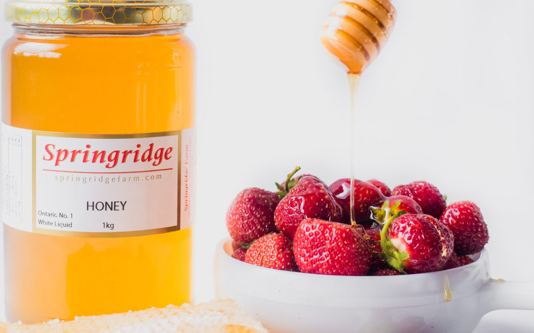 Jar of Honey and a bowl of strawberries